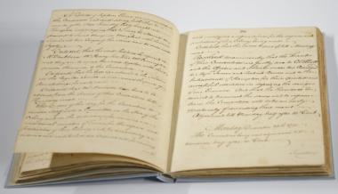 An old records book yellowed with age written in pen with scripted font that contains accounts from Patrick Henry, George Mason, Thomas Jefferson, and James Madison lies open.